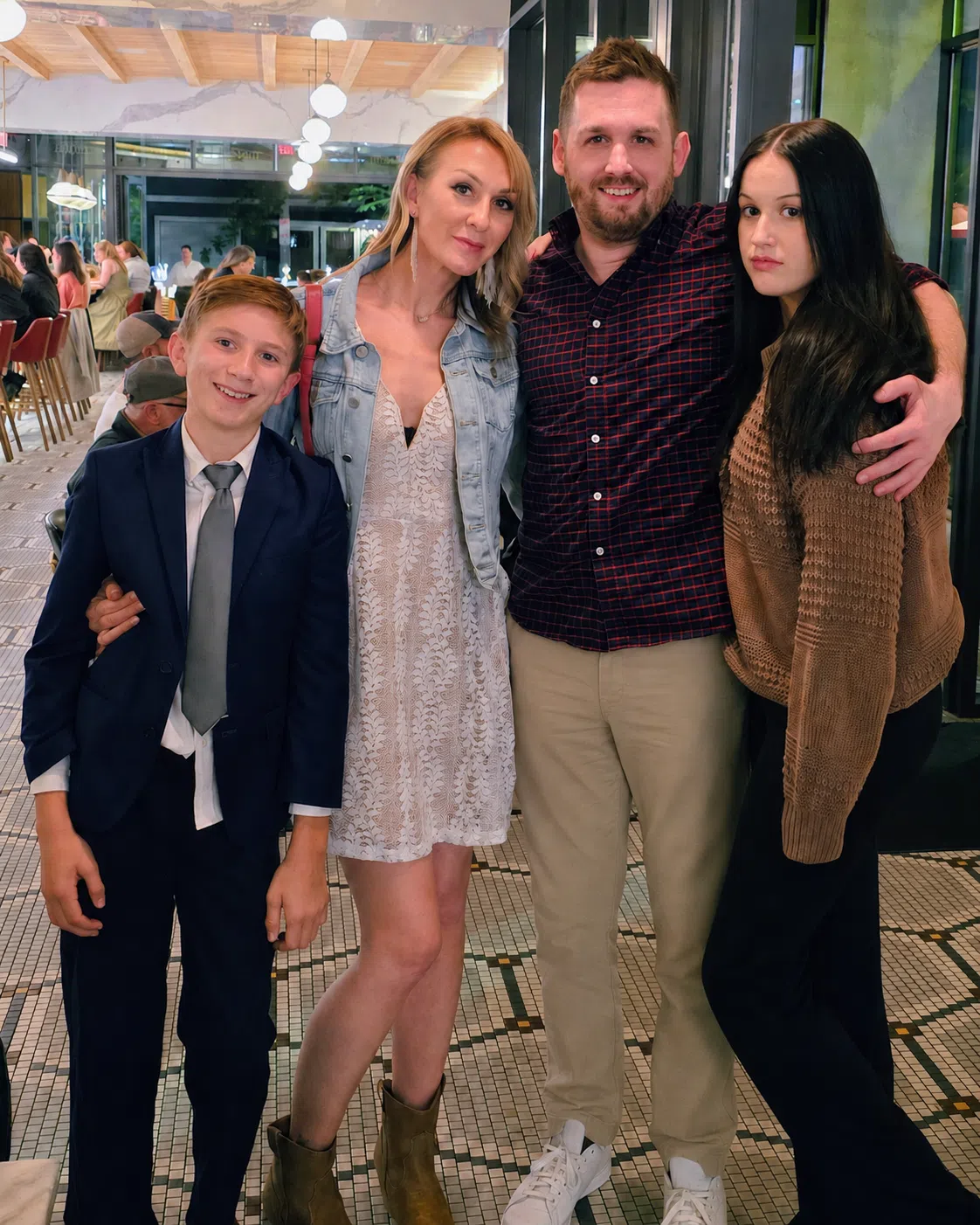 A family of four posing happily in a stylish restaurant setting with a contemporary design.