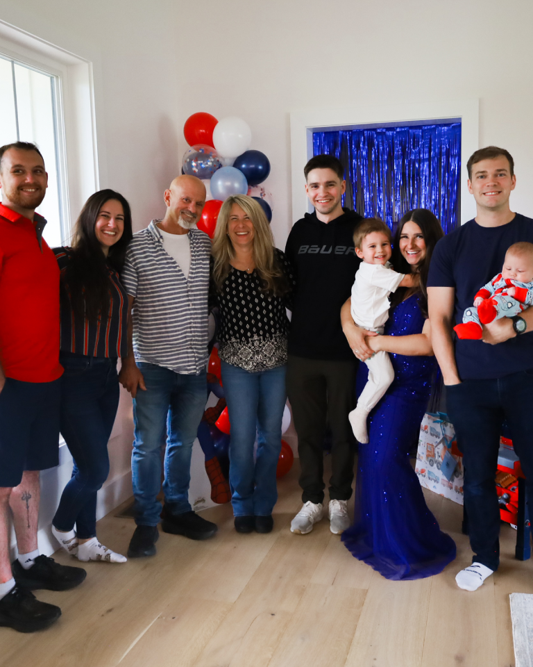 Family gathering celebration with balloons in background, smiles, and joy. Casual attire and happy faces indoors.
