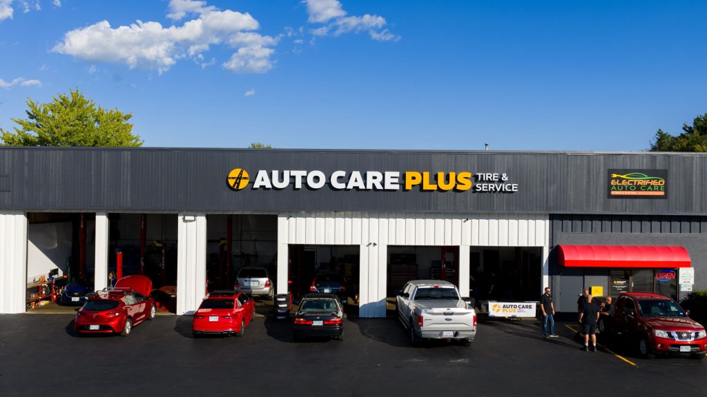 Auto repair shop exterior with parked cars and service bays under a clear blue sky.