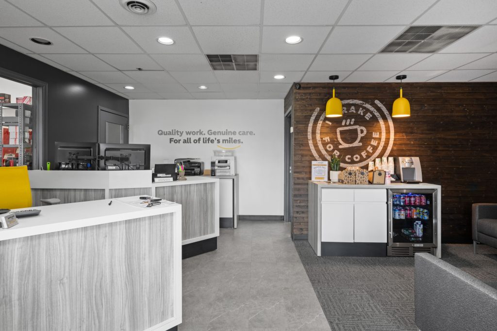 Modern office reception area with coffee station, yellow lights, and motivational wall text. Perfect for professional settings.