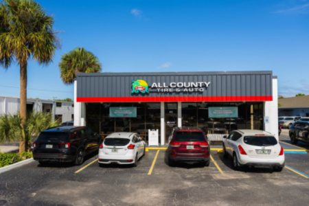 Auto Service Center With Parked Cars, All County Tire & Auto, Sunny Day With Palm Trees.