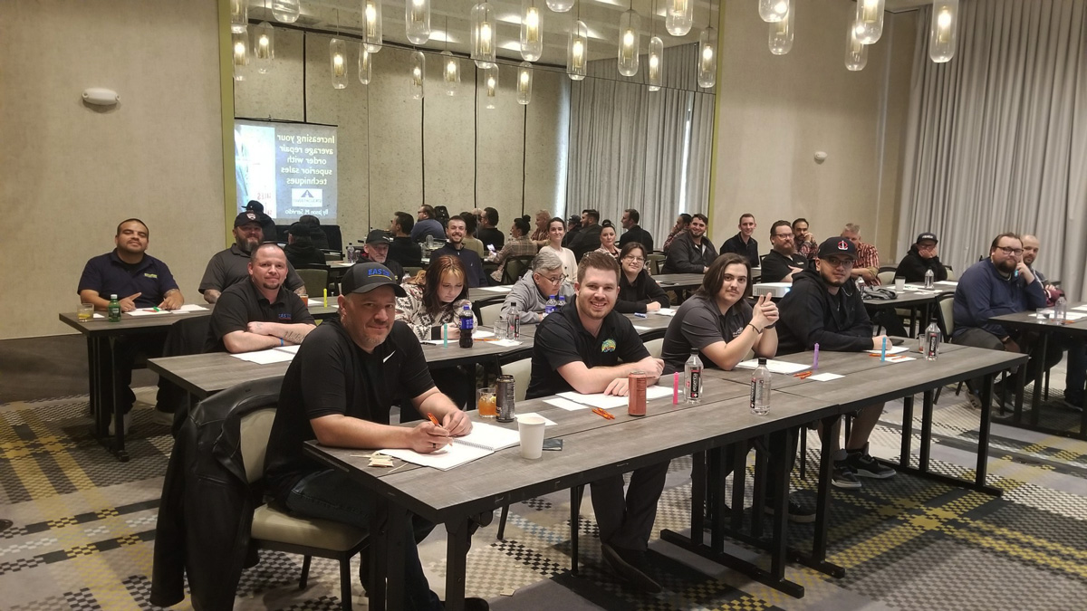 Workshop attendees seated in a conference room, engaging in a session with notebooks and drinks on tables.