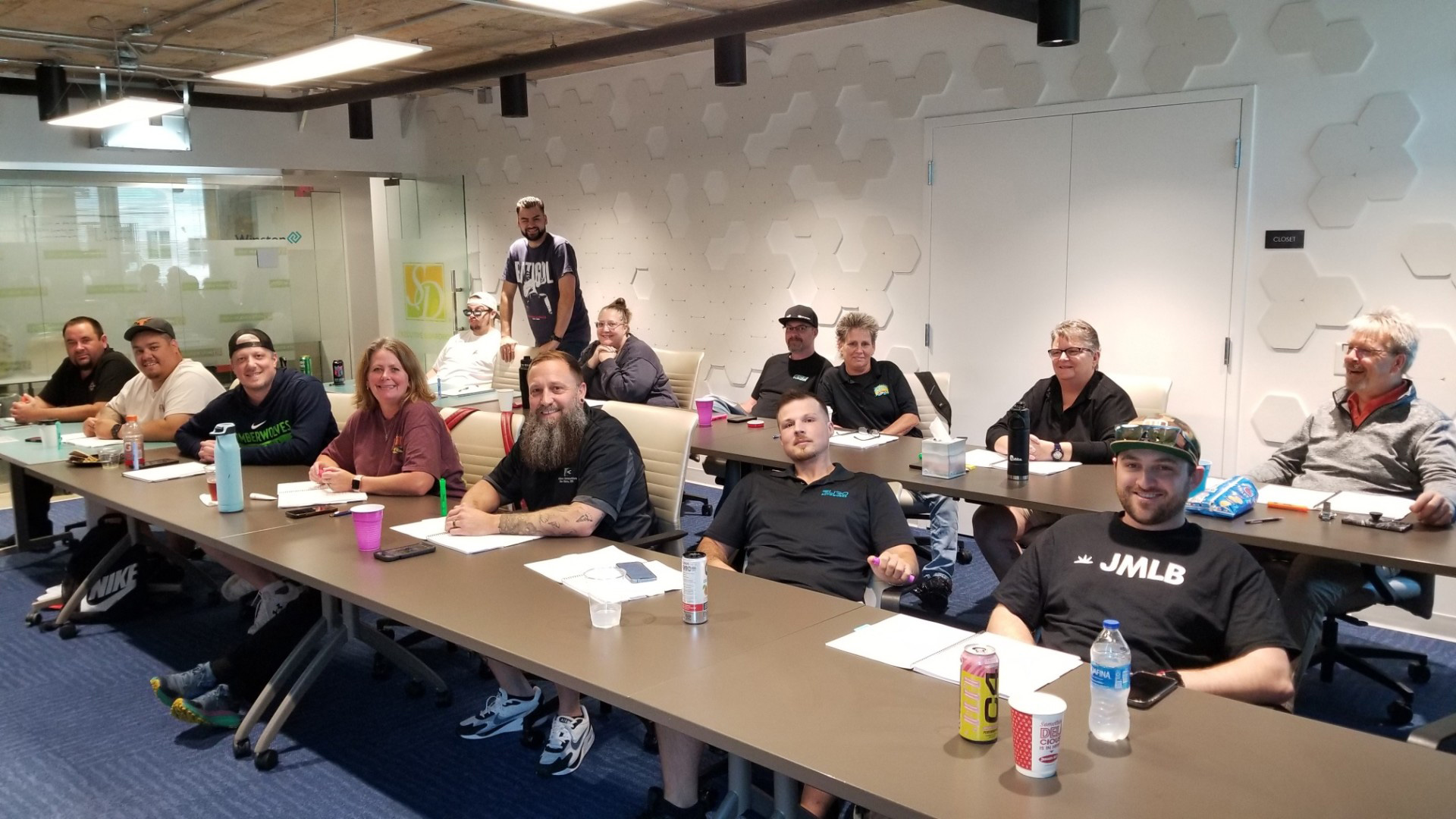 Group of people attending a workshop in a modern conference room with notebooks and drinks on the tables.