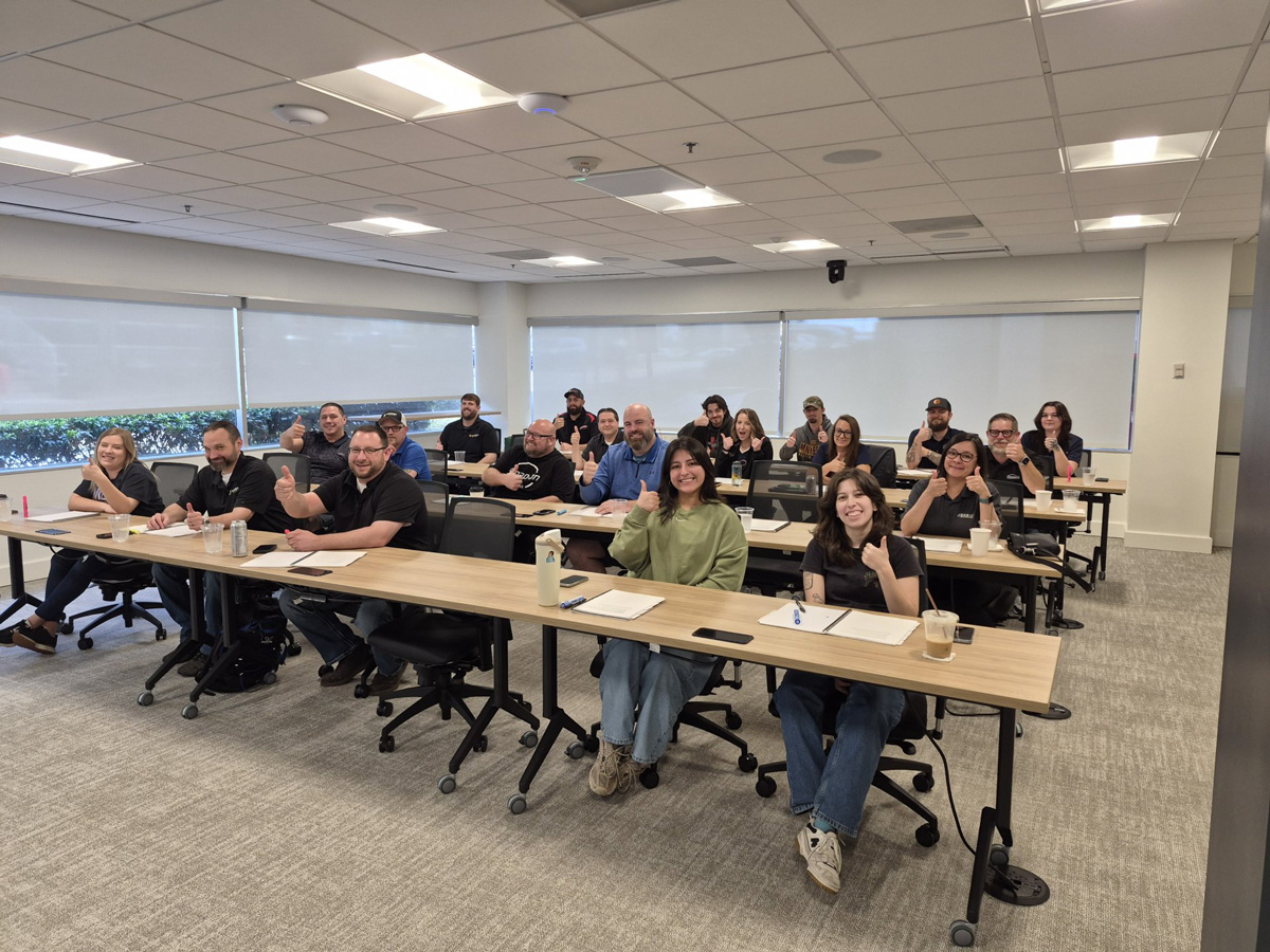 Group of people in a conference room during a workshop, smiling and giving thumbs-up gestures.