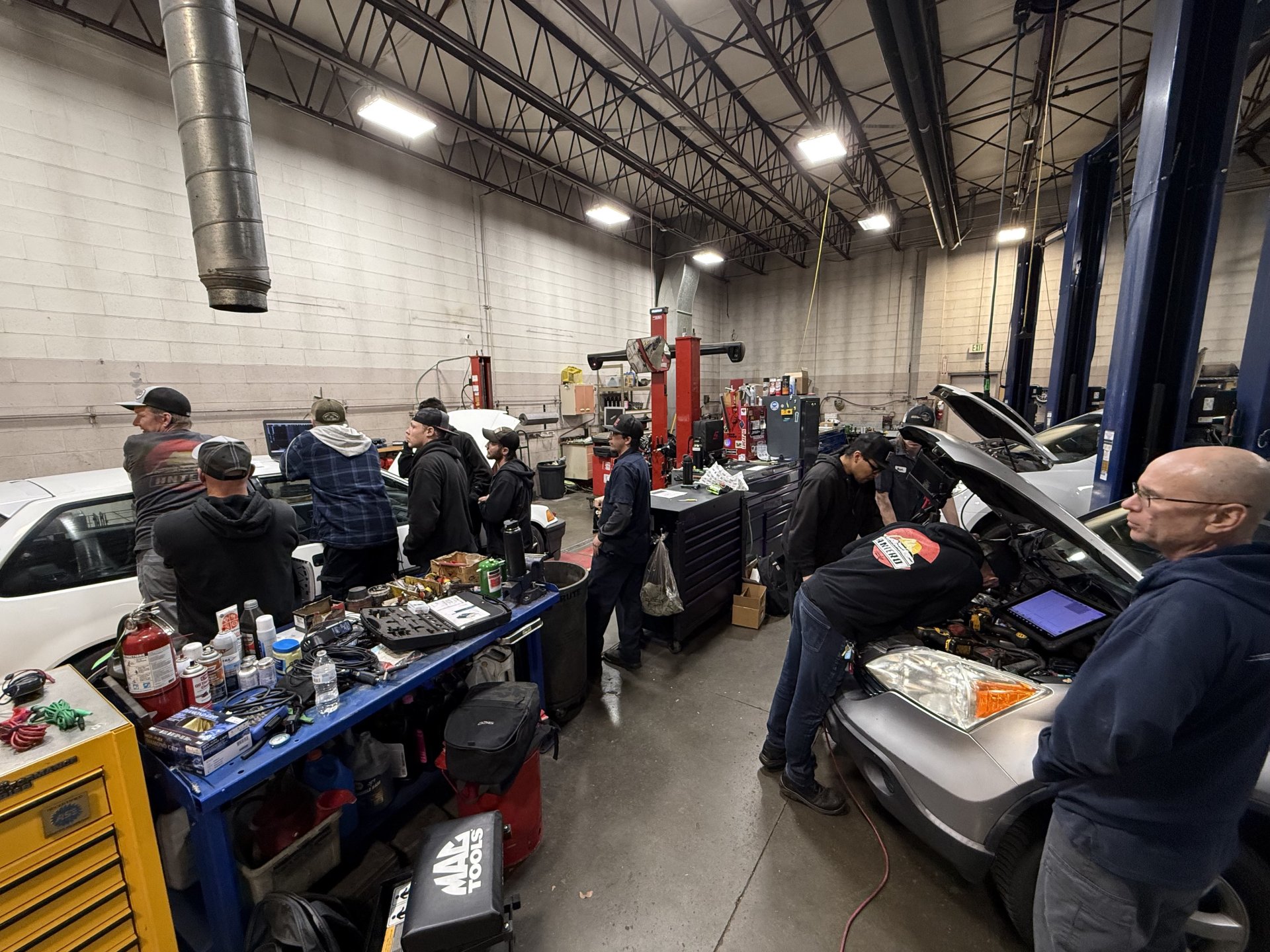 Mechanics working in a busy auto repair shop, surrounded by tools and equipment, diagnosing a car issue.