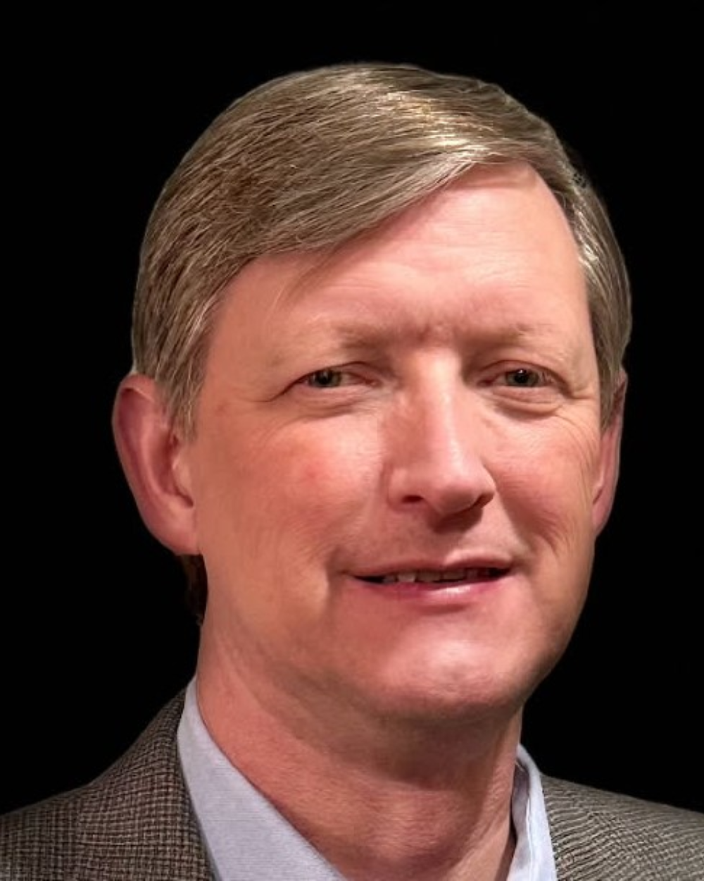 Portrait of a man in a suit with a neutral expression on a black background.
