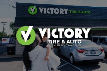 Victory Tire & Auto store entrance with cars parked outside.