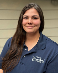 Employee in a blue shirt with Leavenworth Automotive logo, standing against a neutral background, smiling.